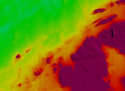 Seafloor bathymetry map of part of the Haig Fras site, showing rock outcrops (purple and red) surrounded by flatter sandy seabed (green).